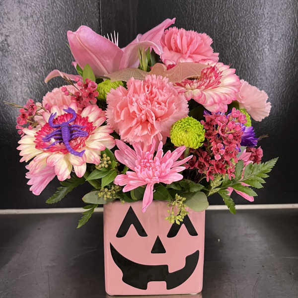 Pink floral arrangement in a jack-o'-lantern vase