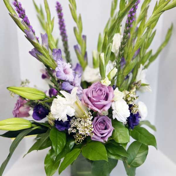 Purple and white flowers arranged in a glass vase