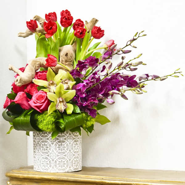 Mixed bouquet in a white patterned vase with red, pink, and purple flowers