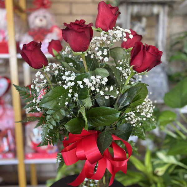 Red roses in a glass vase with baby's breath and a red ribbon