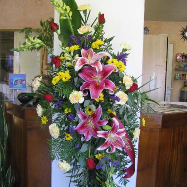 Tall standing floral spray with pink lilies, red roses, and yellow accents