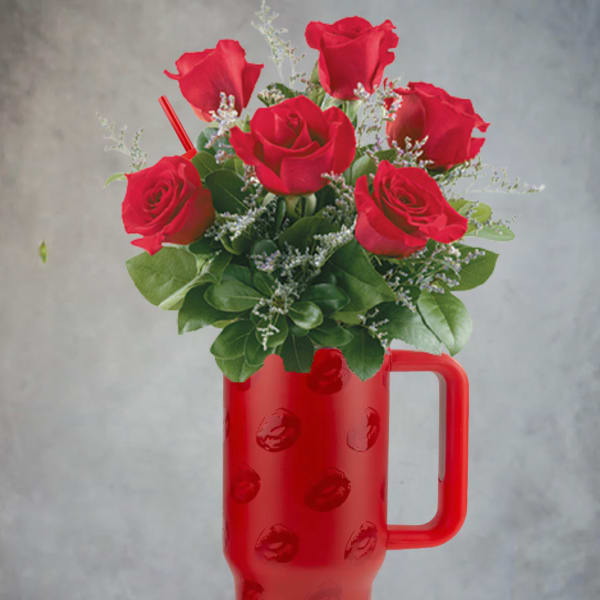 Red roses arranged in a red handled tumbler vase