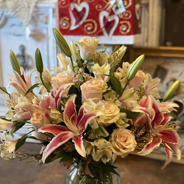 Bouquet of pink lilies, cream roses, and alstroemeria in a glass vase