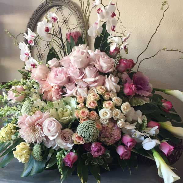Large pastel floral arrangement with roses, orchids, and calla lilies