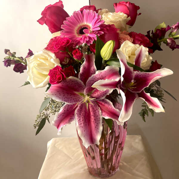 Pink and white roses with lilies and a gerbera daisy in a pink vase