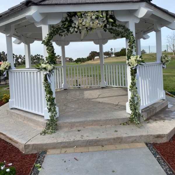 White floral garland decorates a gazebo with greenery and white blooms.