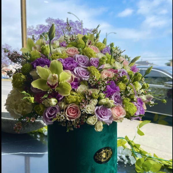 Lavender, pink, and green floral arrangement in a velvet box