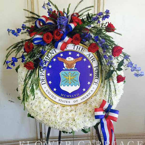 Circular floral wreath with red roses, white flowers, and blue accents around an Air Force emblem