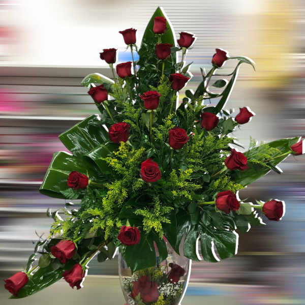 Tall arrangement of red roses with large tropical leaves in a clear glass vase