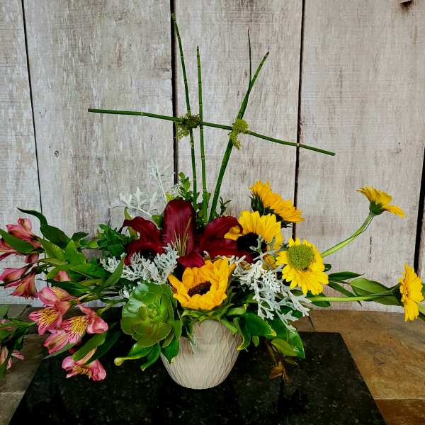 Mixed floral arrangement in a white vase with lilies and sunflowers
