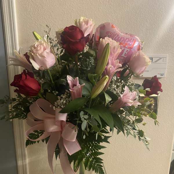 Bouquet of pink and red roses with lilies in a glass vase