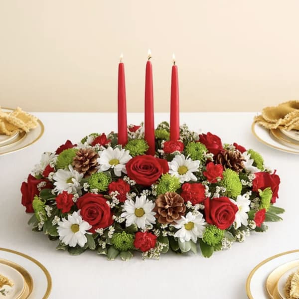 Oval floral centerpiece with red candles and red, white, and green flowers