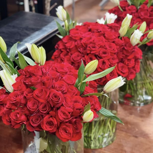 Bouquets of red roses with white lily buds in glass vases