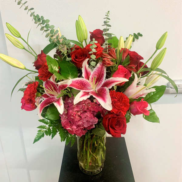 Red roses and pink lilies arranged in a glass vase
