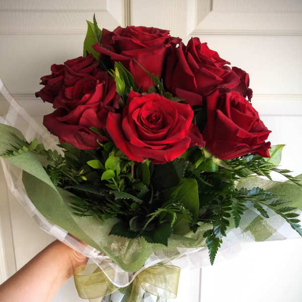 Bouquet of red roses wrapped in green and clear paper