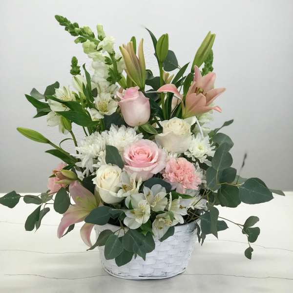 Pink and white mixed flower arrangement in a white basket
