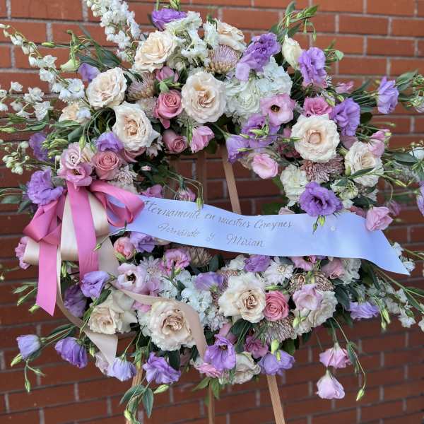 Large pastel floral wreath on an easel with pink and lavender ribbon