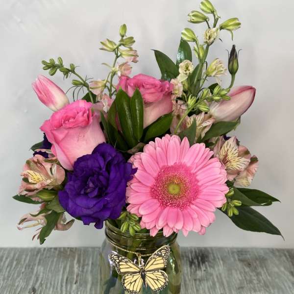 Pink and purple mixed bouquet in a glass jar with a butterfly decoration