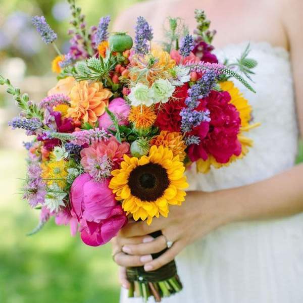 Bride holding a colorful bouquet with sunflowers and mixed blooms