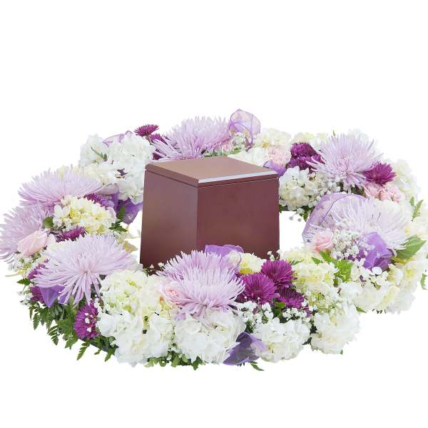 Lavender and white floral wreath surrounding a brown cremation urn box