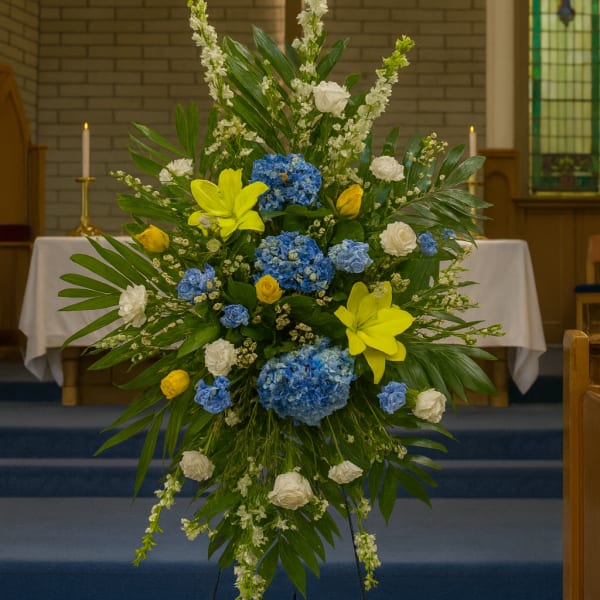 Tall floral spray with blue, yellow, and white flowers in a church