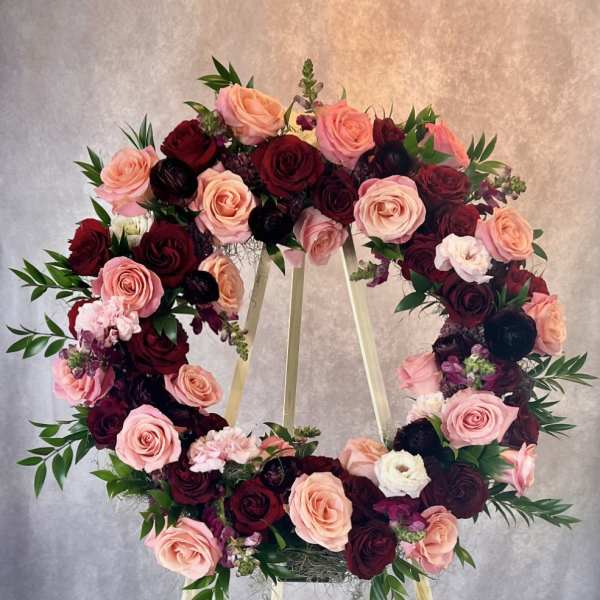 Heart-shaped wreath of pink and burgundy roses on a stand