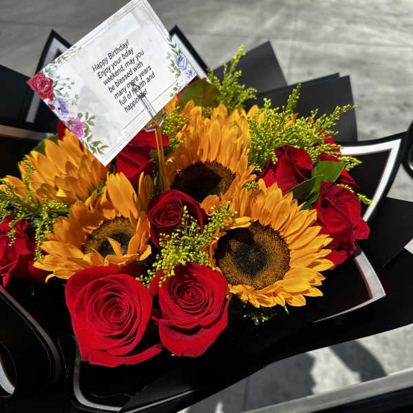 Bouquet of red roses and sunflowers with a birthday card