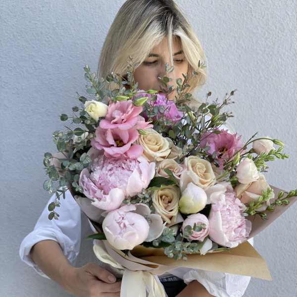 Large bouquet of pink and cream flowers wrapped in paper