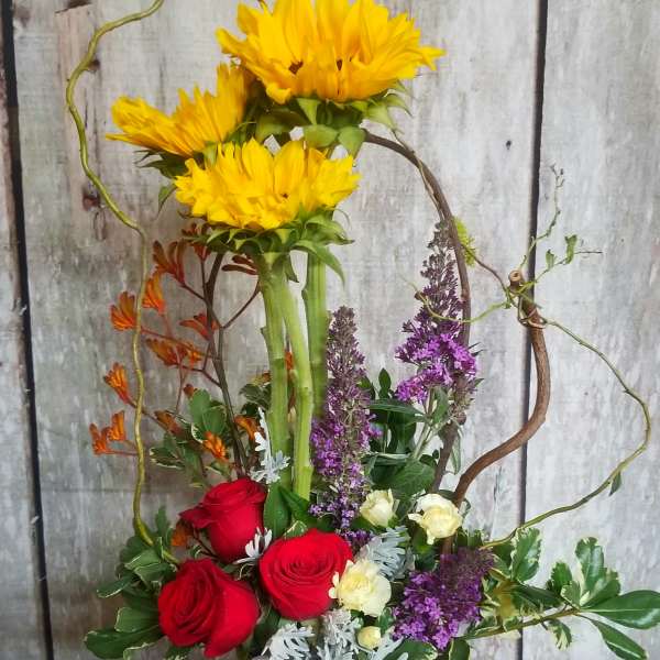 Sunflower and rose arrangement in a round metal container
