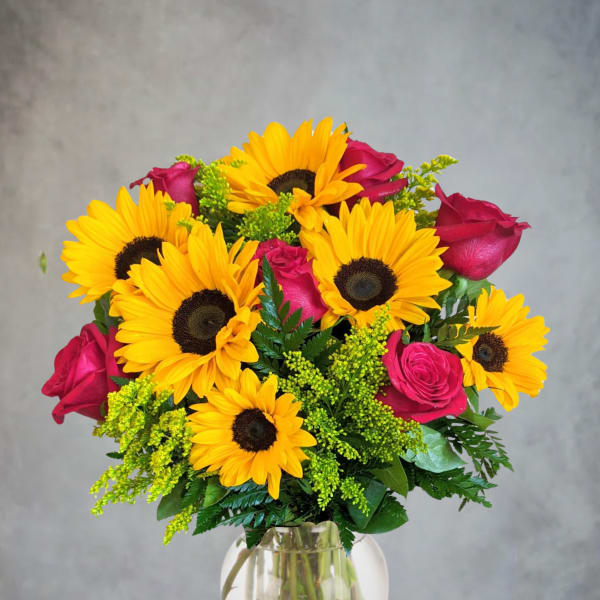 Bouquet of yellow sunflowers and pink roses in a clear glass vase