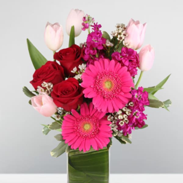 Pink and red mixed bouquet in a clear rectangular vase