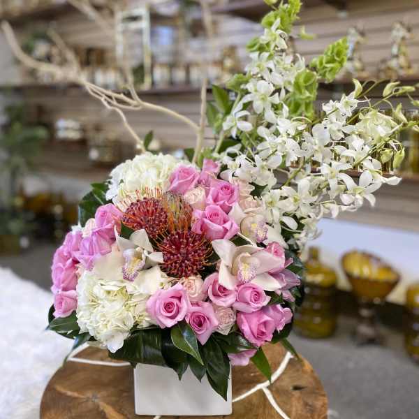 Pink roses and white orchids arranged in a white box