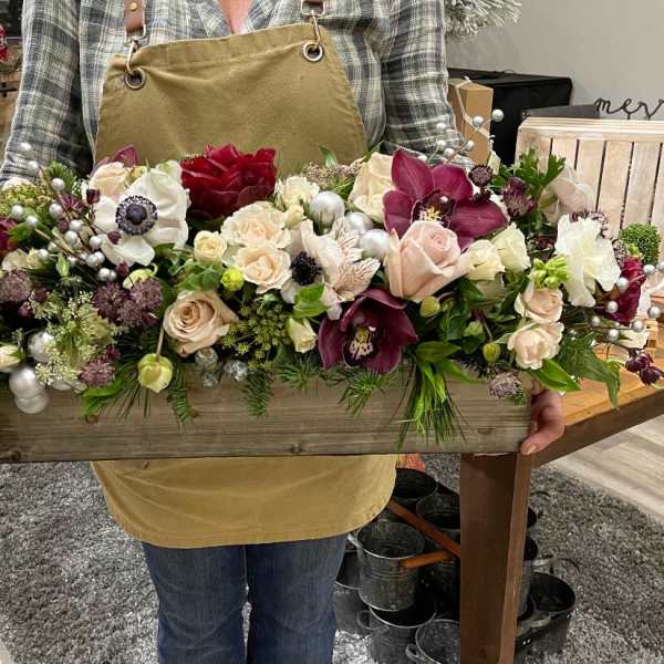 Low wooden box centerpiece with blush and burgundy flowers, white blooms, and silver ornament accents.