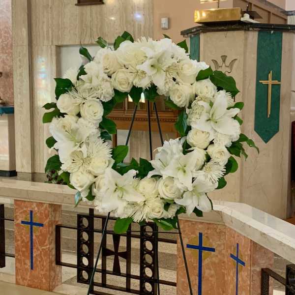 White floral wreath on a stand in a church interior
