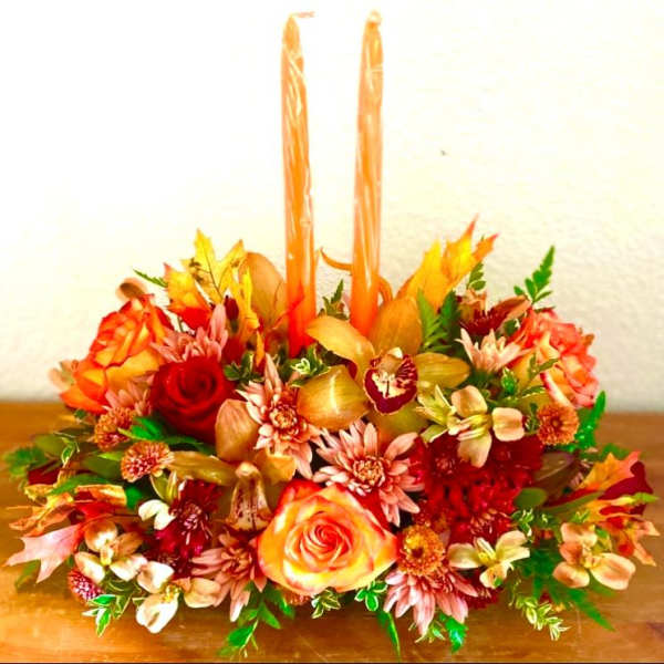 Autumn floral centerpiece with two tall orange candles