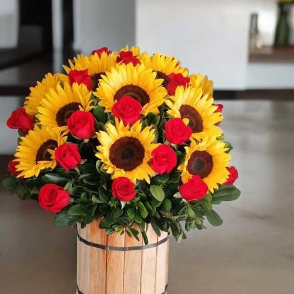 Sunflowers and red roses arranged in a wooden container