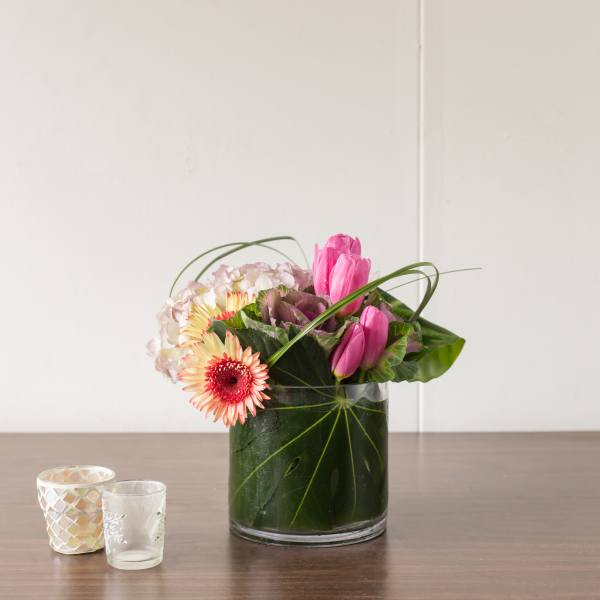 Pink tulips and gerbera daisies arranged in a glass vase