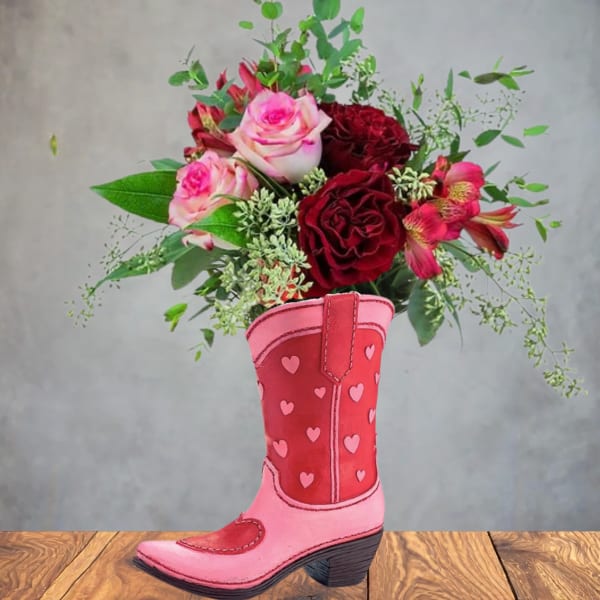 Pink and red roses with accent flowers in a heart-patterned pink cowboy boot vase