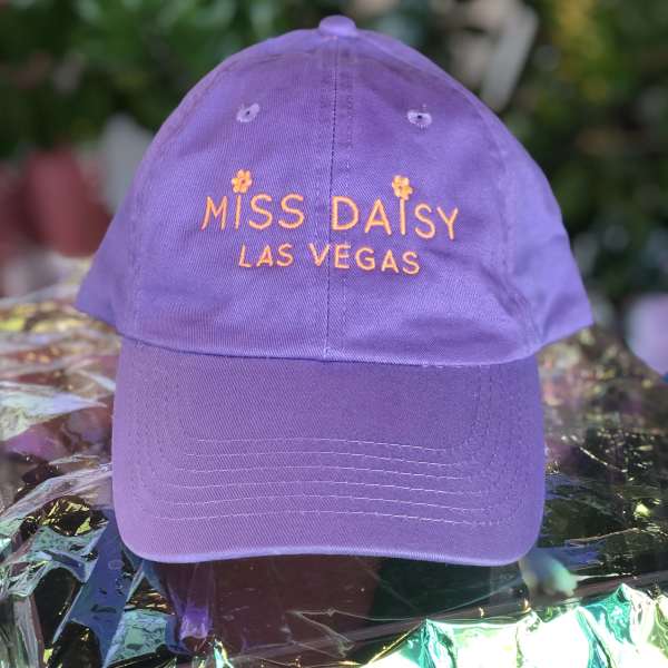 Purple baseball cap with orange embroidered text reading "Miss Daisy Las Vegas"