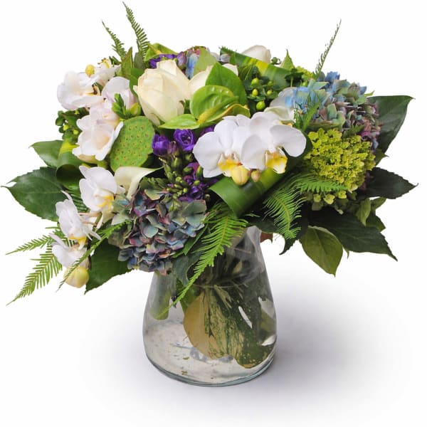 Mixed bouquet of white orchids, hydrangeas, and roses in a glass vase