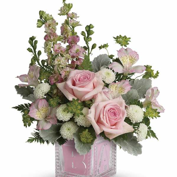 Pink roses and mixed blooms arranged in a clear glass cube vase