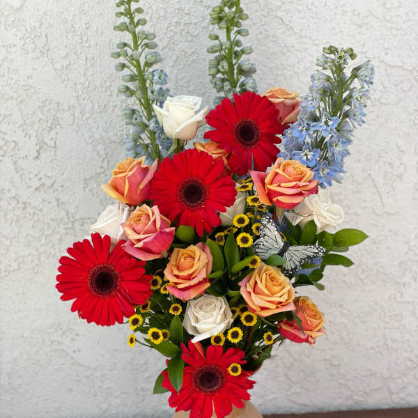 Mixed bouquet in a beige vase with red gerberas and peach roses