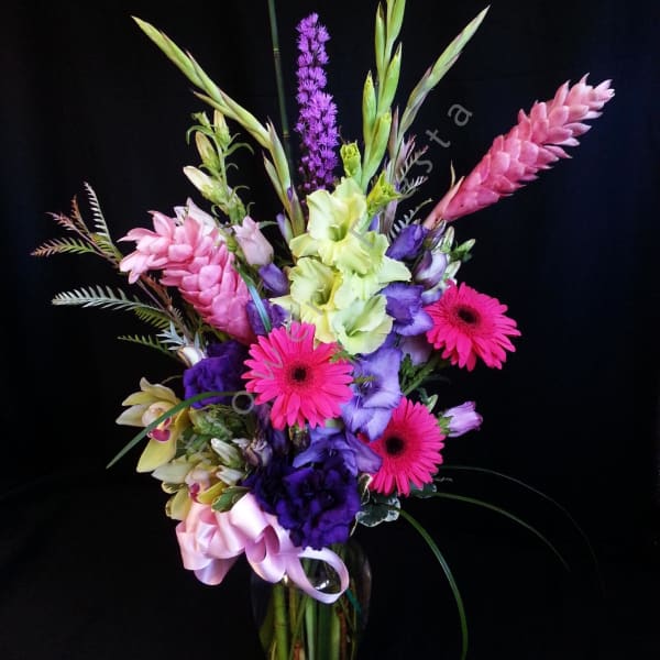 Tall mixed bouquet in a glass vase with pink, purple, and green blooms