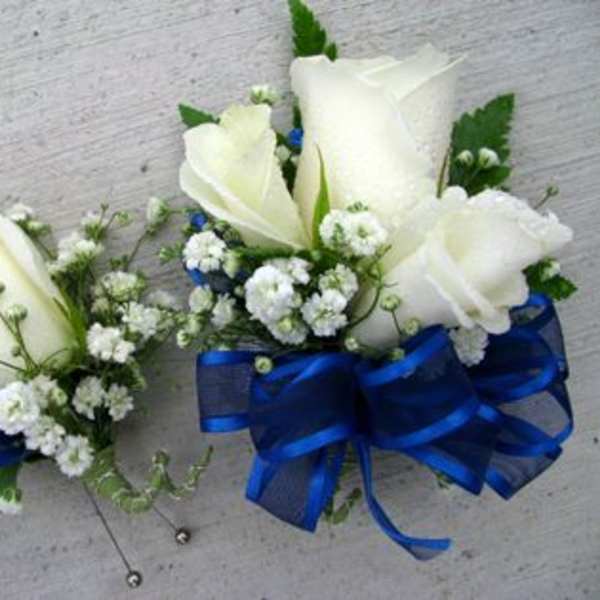 Two white rose corsages with blue ribbon bows