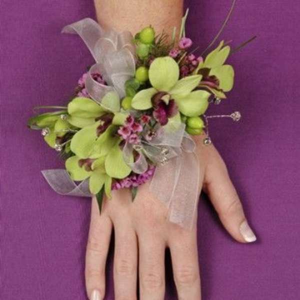 Green orchid wrist corsage with pink accents and sheer ribbon