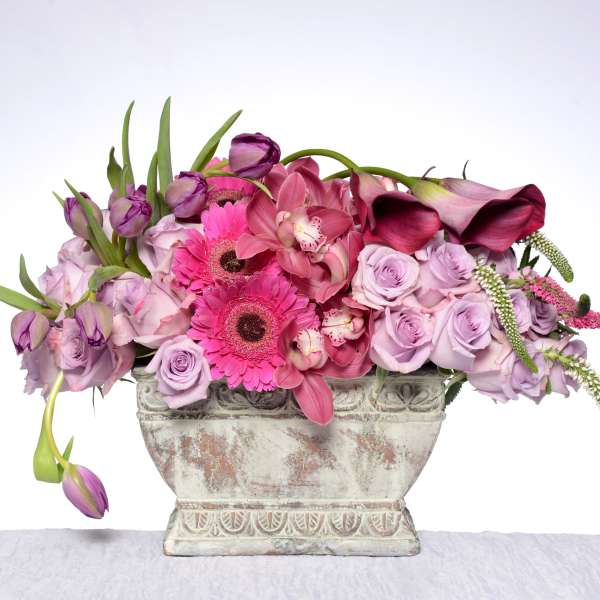 Pink and lavender floral arrangement in a decorative stone vase