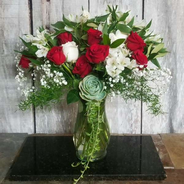 Red and white roses in a glass vase with baby’s breath