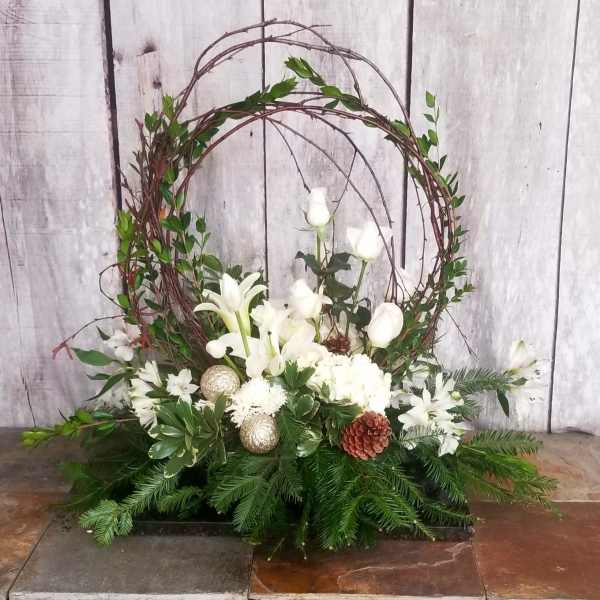White floral arrangement with a twig wreath and evergreen base