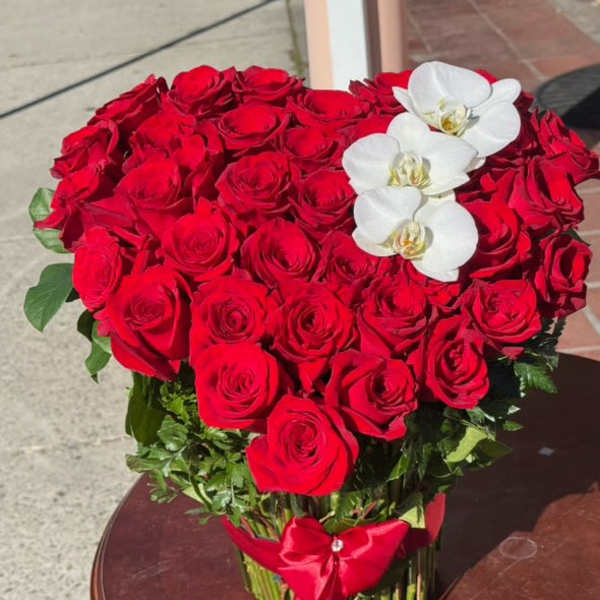 Heart-shaped bouquet of red roses with white orchids and a red ribbon