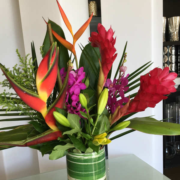 Tropical bouquet with red heliconia and purple orchids in a glass vase